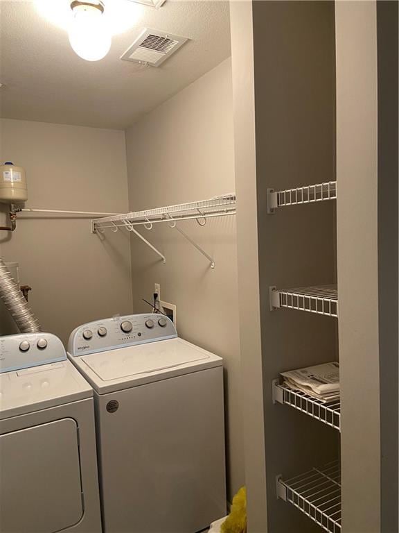 clothes washing area with laundry area, washing machine and dryer, and visible vents