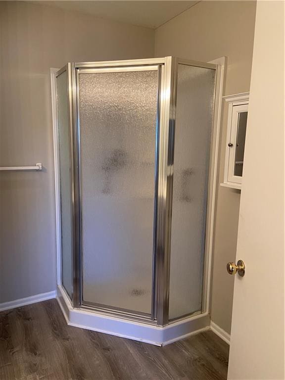 bathroom featuring a stall shower, baseboards, and wood finished floors