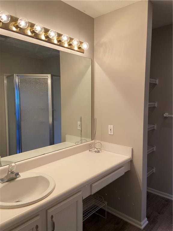 bathroom with a stall shower, baseboards, wood finished floors, and vanity