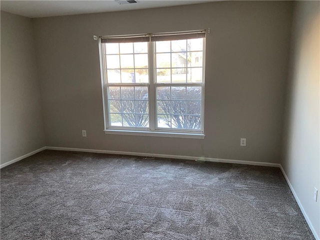 carpeted spare room with a wealth of natural light, visible vents, and baseboards