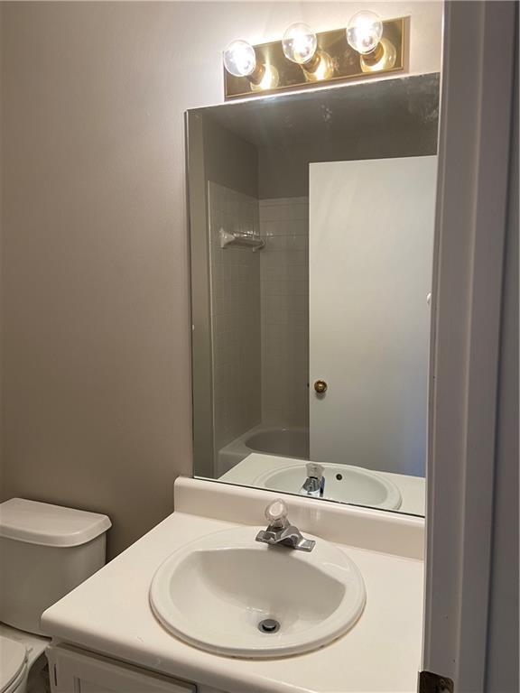 bathroom featuring toilet, a shower, and vanity