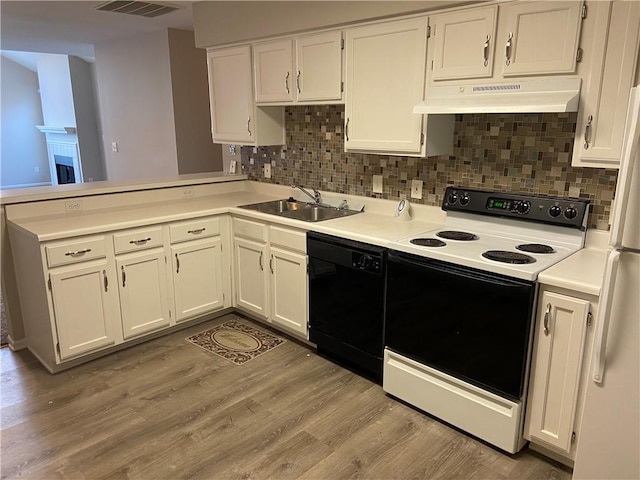 kitchen featuring range with electric stovetop, light wood-style flooring, a sink, dishwasher, and under cabinet range hood