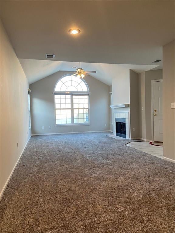 unfurnished living room with carpet floors, visible vents, a tiled fireplace, and lofted ceiling