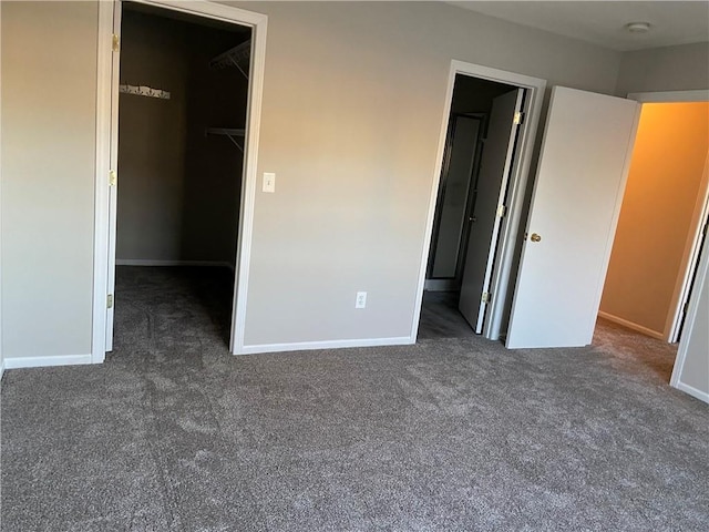 unfurnished bedroom featuring carpet, baseboards, and a walk in closet