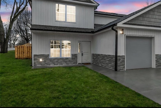 view of front of home featuring a garage, fence, driveway, stone siding, and a front yard