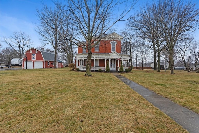 italianate home featuring covered porch, an outdoor structure, a barn, a detached garage, and a front lawn