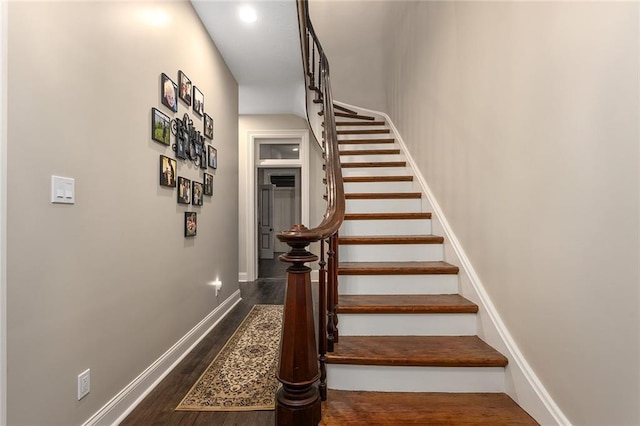 staircase featuring baseboards and wood finished floors