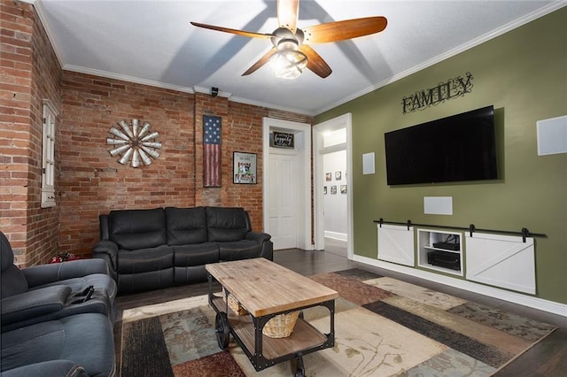 living room with ceiling fan, brick wall, wood finished floors, baseboards, and ornamental molding