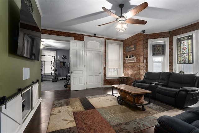 living room featuring brick wall, a barn door, and wood finished floors