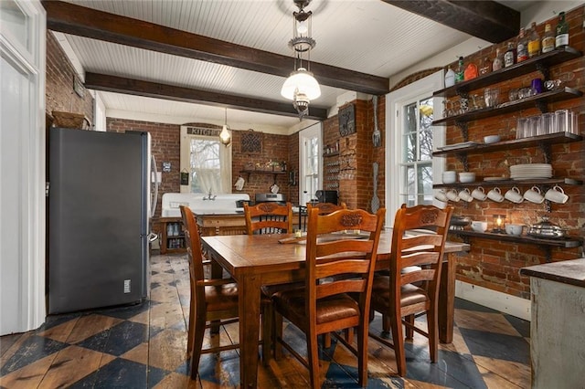 dining space with brick wall and beamed ceiling