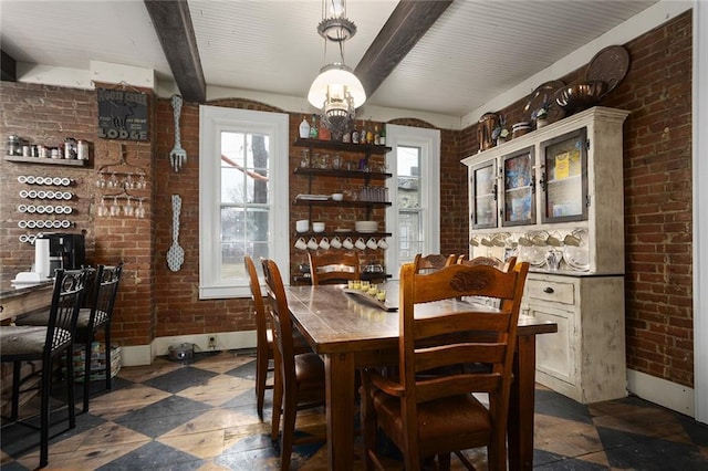 dining area featuring a healthy amount of sunlight, beamed ceiling, and brick wall