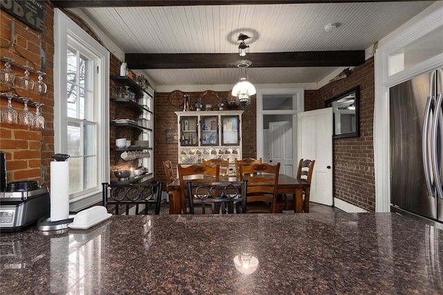 dining room with brick wall, beamed ceiling, and granite finish floor