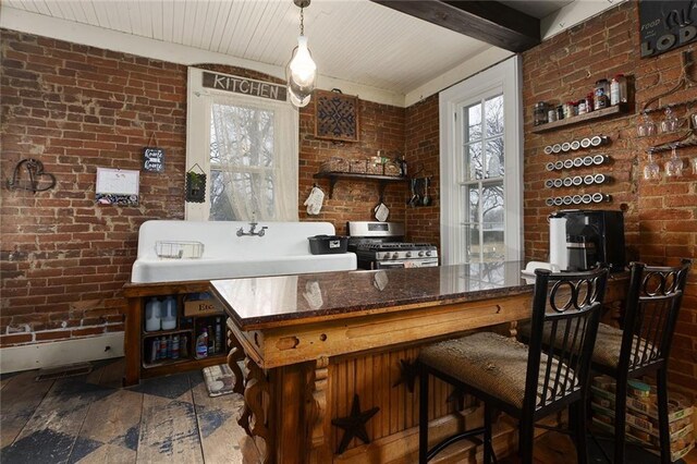 bar with brick wall, stainless steel gas range oven, plenty of natural light, and a sink