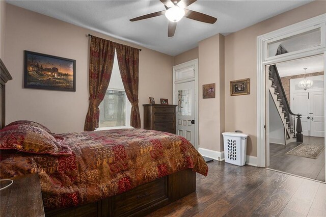 bedroom with baseboards, dark wood finished floors, and ceiling fan with notable chandelier