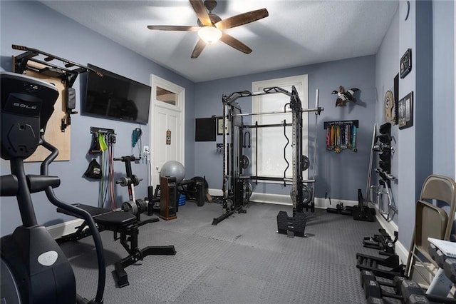 workout area featuring a textured ceiling, a ceiling fan, and baseboards