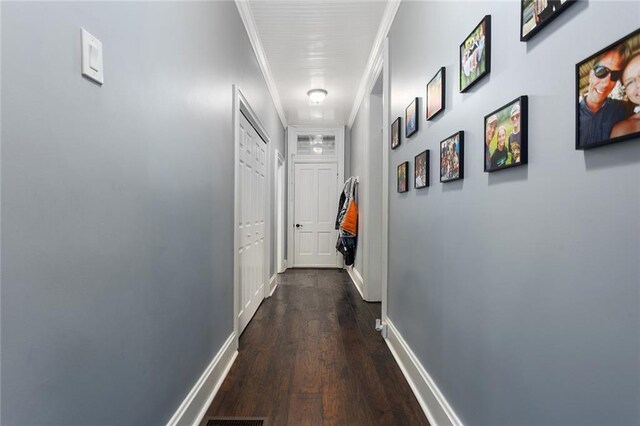 corridor with ornamental molding, dark wood finished floors, and baseboards