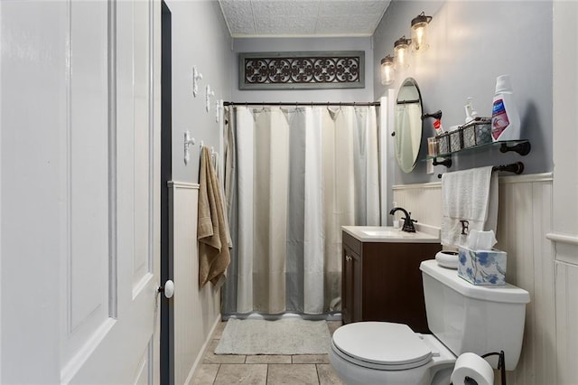 bathroom featuring wainscoting, toilet, a shower with curtain, tile patterned floors, and vanity