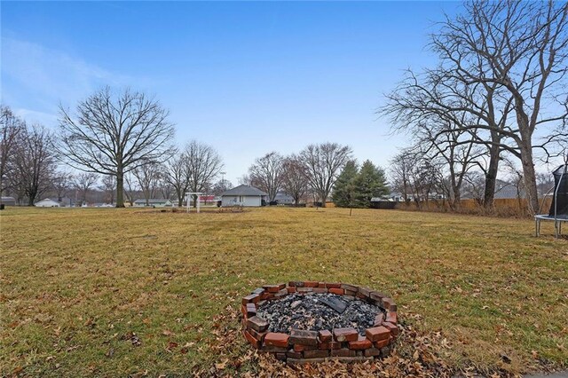 view of yard with an outdoor fire pit and a trampoline