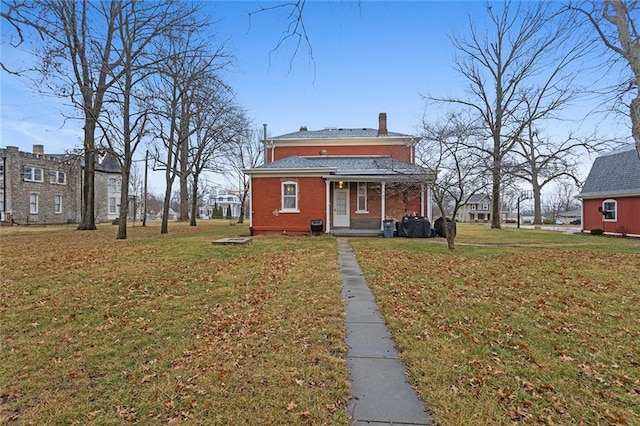 exterior space featuring brick siding, a chimney, covered porch, and a front yard