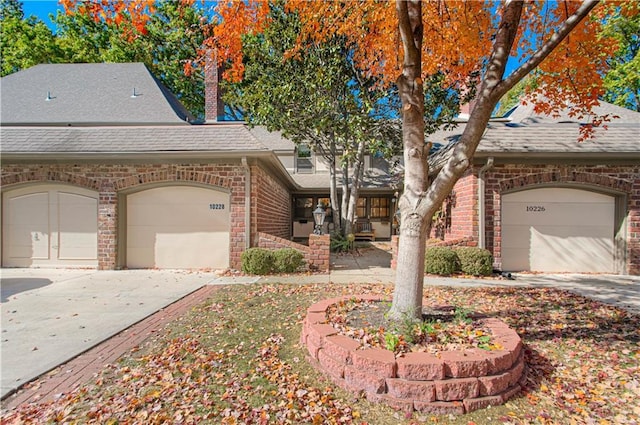 view of front facade with a garage, roof with shingles, concrete driveway, and brick siding