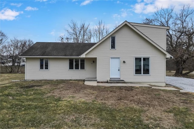 back of property featuring a shingled roof, entry steps, and a lawn