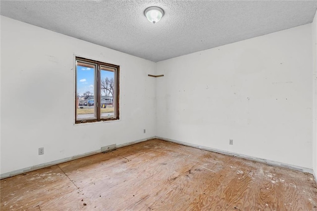 unfurnished room featuring baseboards and a textured ceiling