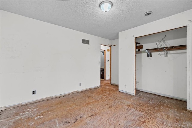 unfurnished bedroom with a textured ceiling, a closet, and visible vents