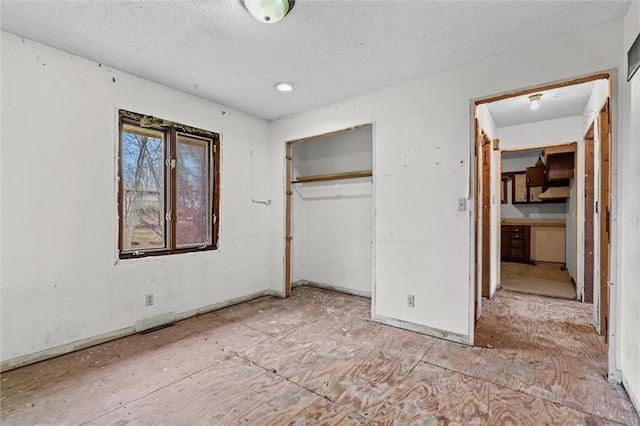 unfurnished bedroom with a closet, a textured ceiling, and baseboards