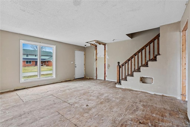 unfurnished living room with stairway and a textured ceiling