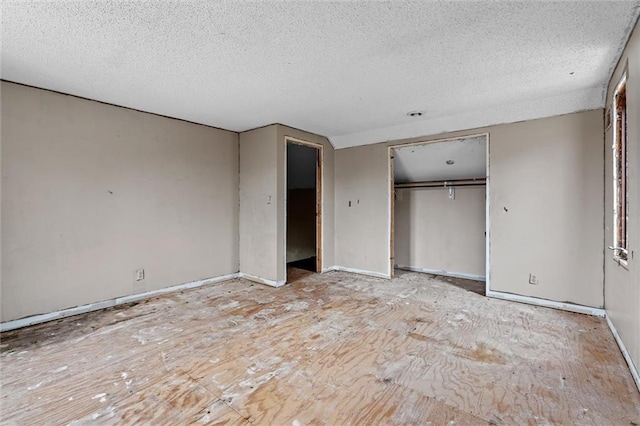 unfurnished bedroom with a textured ceiling, baseboards, and a closet