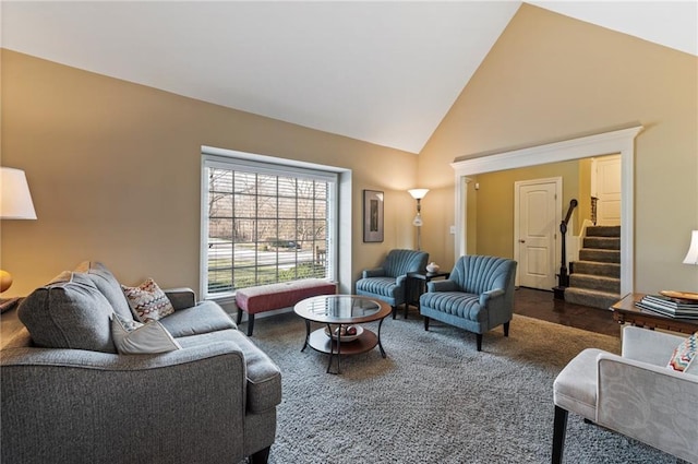 living room with carpet flooring, high vaulted ceiling, and stairs