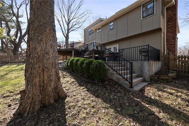 rear view of house featuring stairs, a deck, and fence