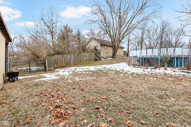 snowy yard with a trampoline and fence