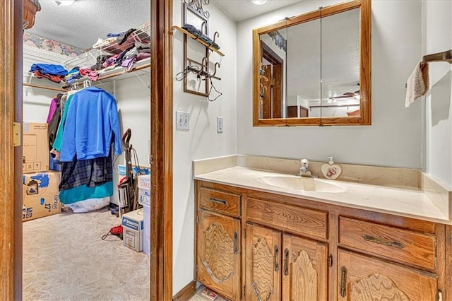 bathroom with a walk in closet, vanity, and a textured ceiling