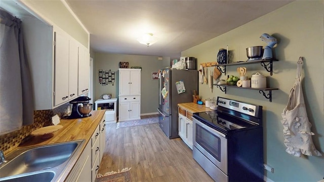 kitchen featuring appliances with stainless steel finishes, a sink, butcher block countertops, white cabinetry, and light wood-type flooring