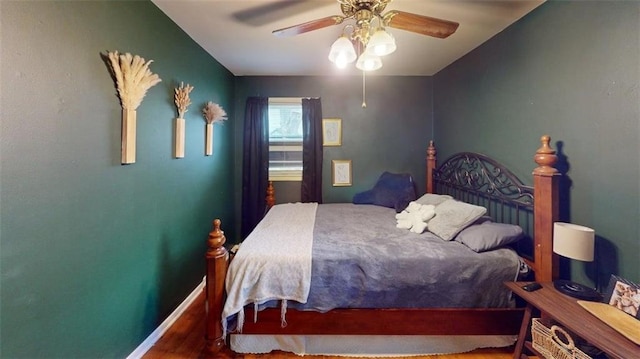 bedroom with a ceiling fan, baseboards, and wood finished floors