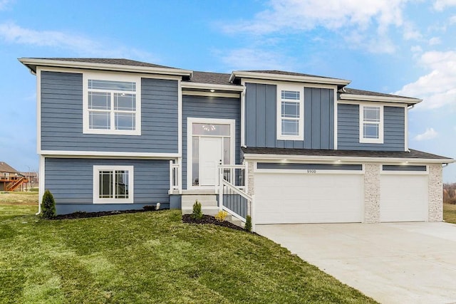 bi-level home with an attached garage, concrete driveway, board and batten siding, and a front yard