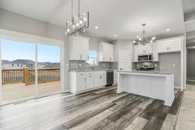 kitchen with backsplash, appliances with stainless steel finishes, white cabinets, and dark wood finished floors