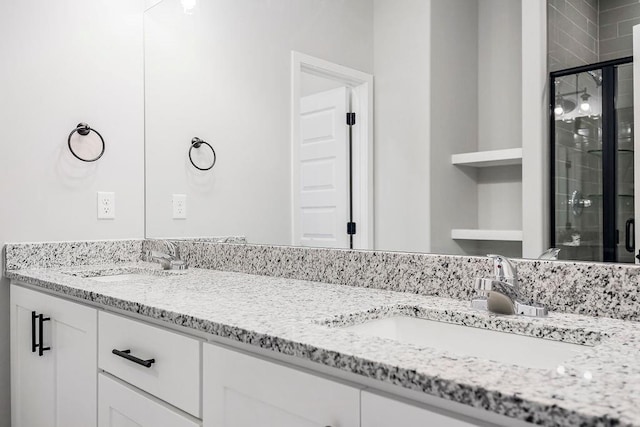 bathroom featuring double vanity, a stall shower, and a sink