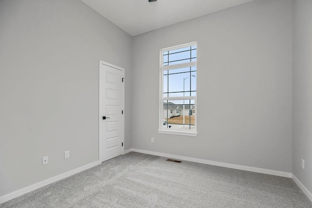 empty room with baseboards, visible vents, and carpet flooring