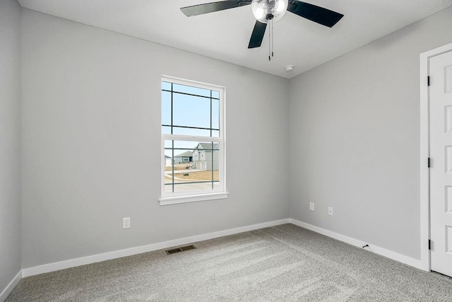 carpeted spare room featuring baseboards, visible vents, and a ceiling fan