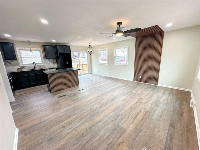 kitchen featuring baseboards, a sink, a wealth of natural light, and light wood-style floors