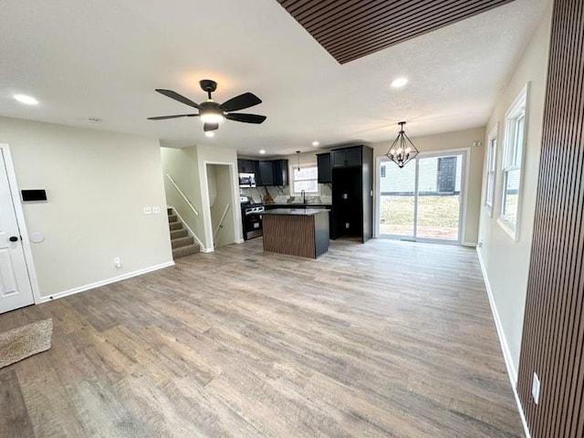 kitchen featuring recessed lighting, appliances with stainless steel finishes, open floor plan, light wood-type flooring, and baseboards