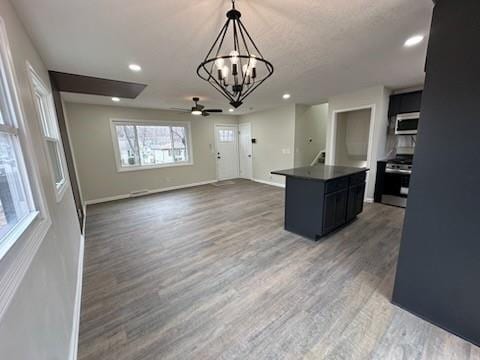 kitchen with a center island, stainless steel appliances, dark countertops, an inviting chandelier, and light wood-type flooring