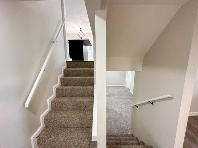 staircase featuring carpet flooring and baseboards