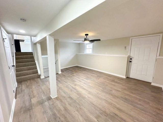 basement with light wood-style flooring, stairs, baseboards, and a ceiling fan