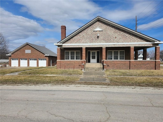 view of front of property featuring covered porch, brick siding, and a chimney