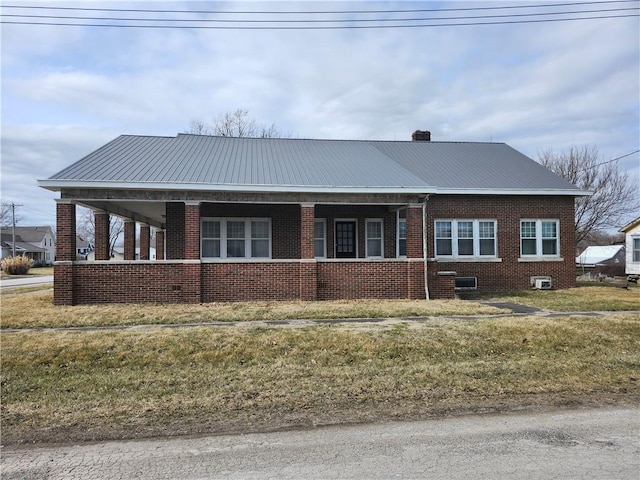 view of front of home with covered porch, brick siding, and metal roof