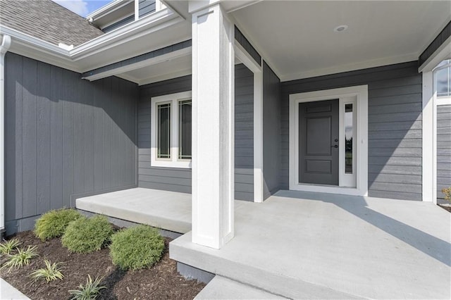 doorway to property with covered porch and roof with shingles