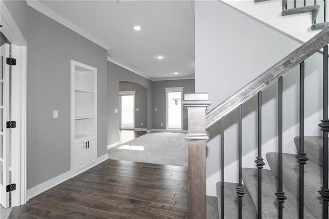 interior space featuring baseboards, arched walkways, stairway, ornamental molding, and dark wood-style flooring